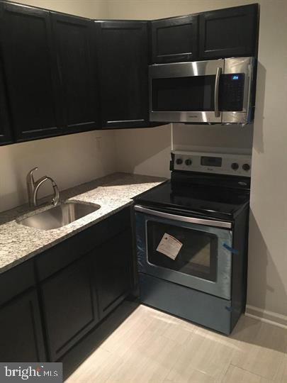 kitchen featuring light stone countertops, appliances with stainless steel finishes, and sink