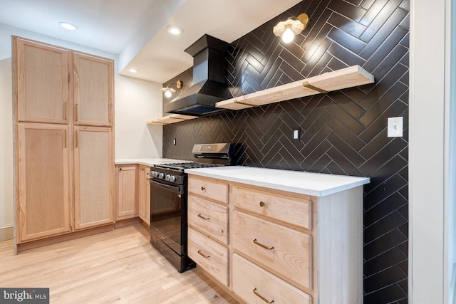 kitchen featuring light brown cabinets, premium range hood, black gas stove, light hardwood / wood-style flooring, and backsplash