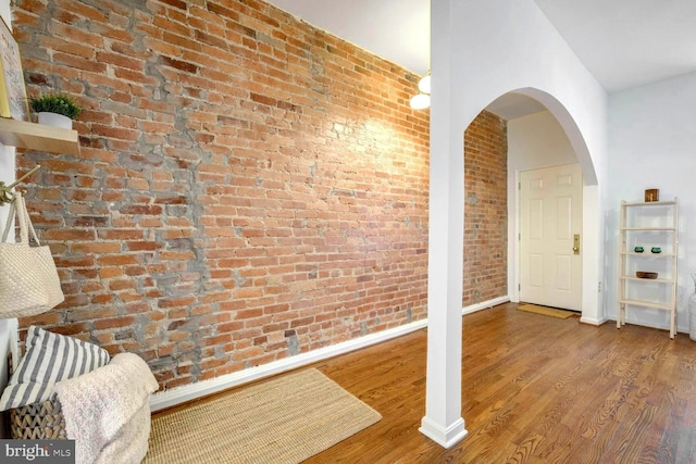 corridor featuring wood-type flooring and brick wall