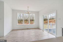 unfurnished dining area featuring light wood-type flooring and a notable chandelier