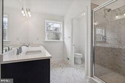 bathroom featuring vanity, toilet, and a shower with shower door