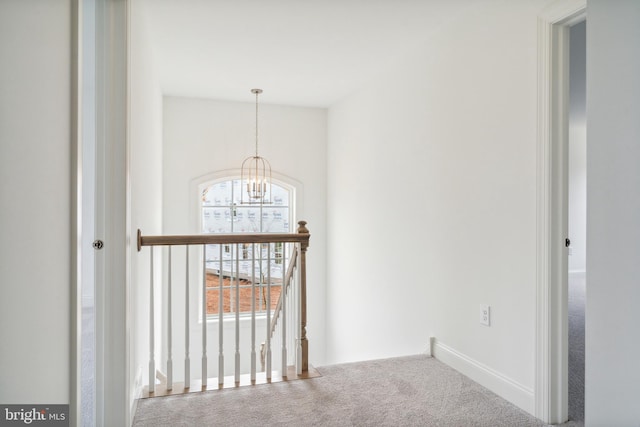 corridor featuring a chandelier and carpet floors