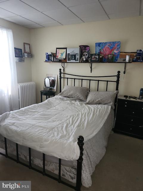 bedroom with a drop ceiling and radiator