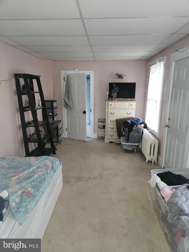 carpeted bedroom featuring a drop ceiling and radiator