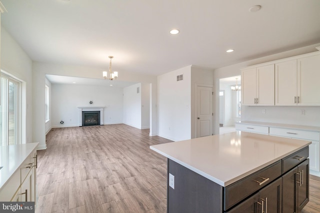 kitchen featuring white cabinetry, an inviting chandelier, light wood-type flooring, hanging light fixtures, and a kitchen island