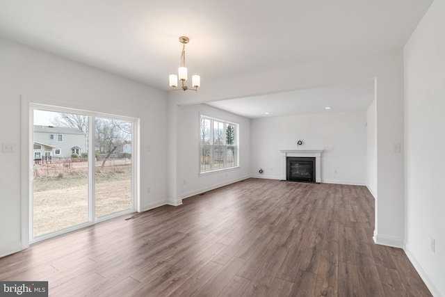 unfurnished living room with an inviting chandelier and dark hardwood / wood-style floors