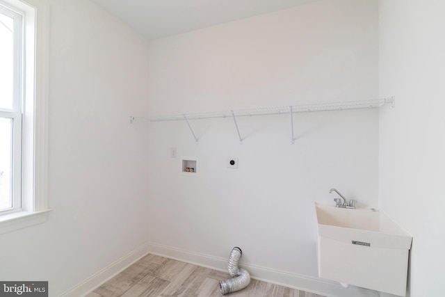 washroom with sink, hookup for an electric dryer, hookup for a washing machine, and light wood-type flooring