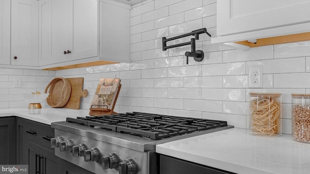 kitchen with white cabinets, gas stovetop, backsplash, and light stone counters