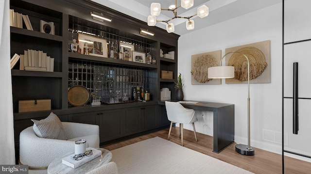 bar featuring hardwood / wood-style floors, an inviting chandelier, and built in shelves