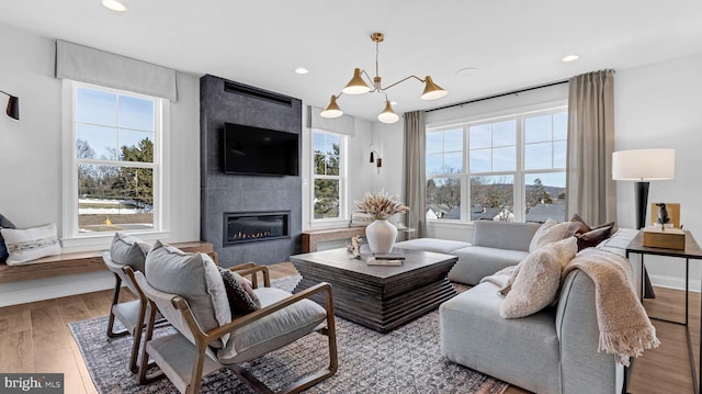 living room with wood-type flooring, a fireplace, and an inviting chandelier