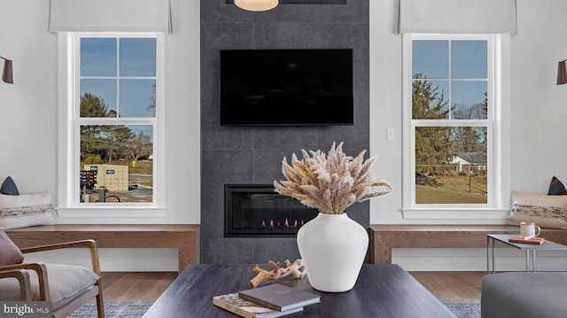 living room with wood-type flooring and a tiled fireplace