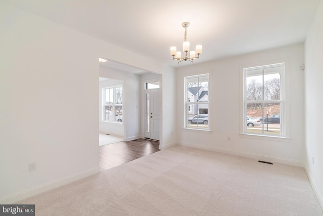 empty room with an inviting chandelier and carpet