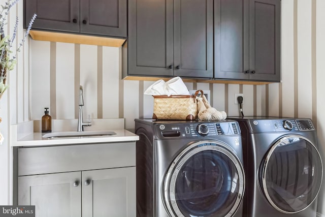 clothes washing area featuring washing machine and dryer, cabinets, and sink