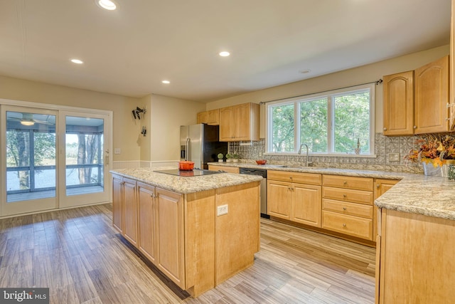 kitchen with decorative backsplash, a kitchen island, light hardwood / wood-style flooring, sink, and stainless steel appliances