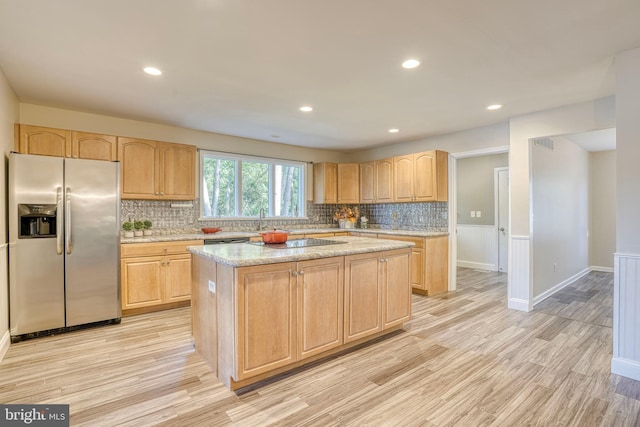 kitchen featuring light brown cabinetry, a center island, appliances with stainless steel finishes, and light hardwood / wood-style flooring