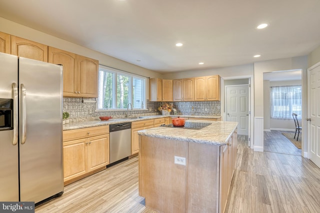 kitchen featuring a kitchen island, light stone countertops, stainless steel appliances, and light wood-type flooring