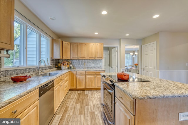 kitchen with appliances with stainless steel finishes, sink, a kitchen island, decorative backsplash, and light hardwood / wood-style flooring