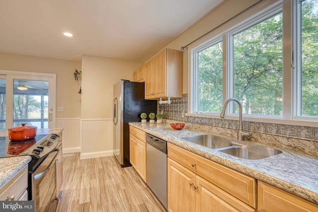 kitchen featuring decorative backsplash, appliances with stainless steel finishes, light brown cabinetry, light wood-type flooring, and sink