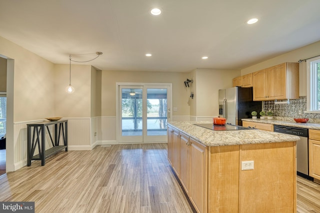 kitchen with decorative backsplash, stainless steel appliances, a center island, decorative light fixtures, and light hardwood / wood-style floors