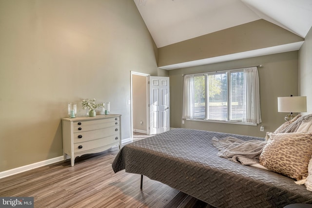 bedroom featuring hardwood / wood-style floors and high vaulted ceiling