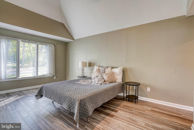 bedroom featuring high vaulted ceiling and light wood-type flooring