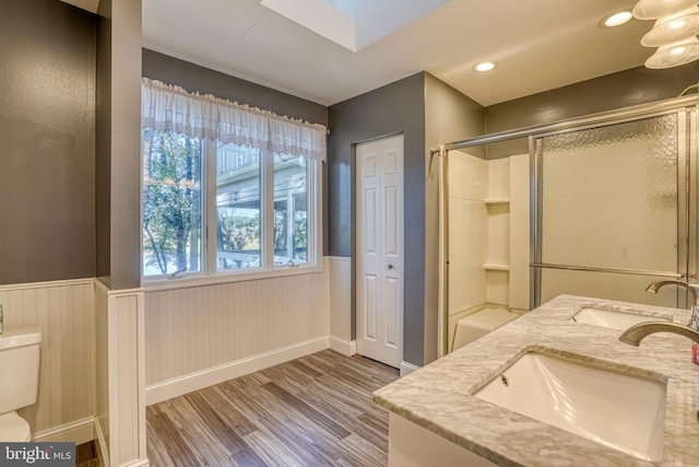 bathroom featuring toilet, hardwood / wood-style flooring, walk in shower, and vanity