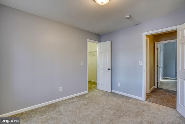 unfurnished bedroom with a closet, a spacious closet, and light colored carpet