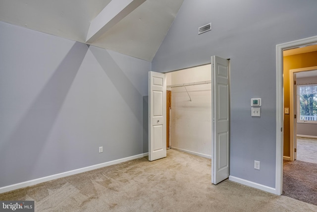 unfurnished bedroom featuring a closet, light carpet, and vaulted ceiling