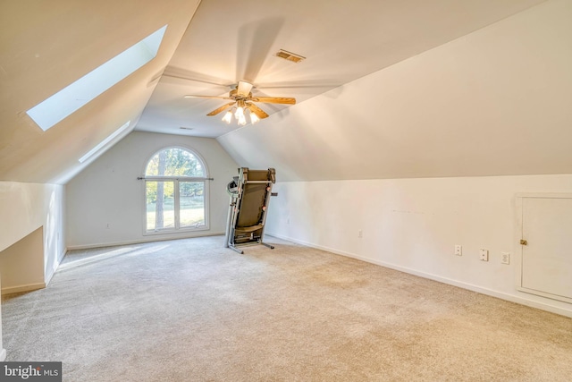 additional living space featuring lofted ceiling with skylight, light carpet, and ceiling fan