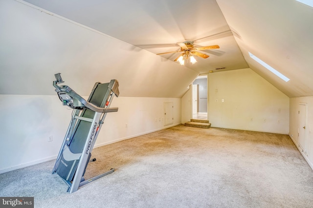 exercise room featuring vaulted ceiling with skylight, carpet floors, and ceiling fan