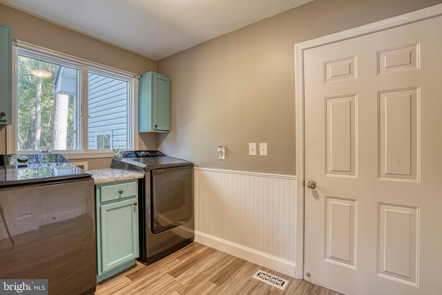 kitchen featuring washer / dryer, green cabinetry, and light wood-type flooring