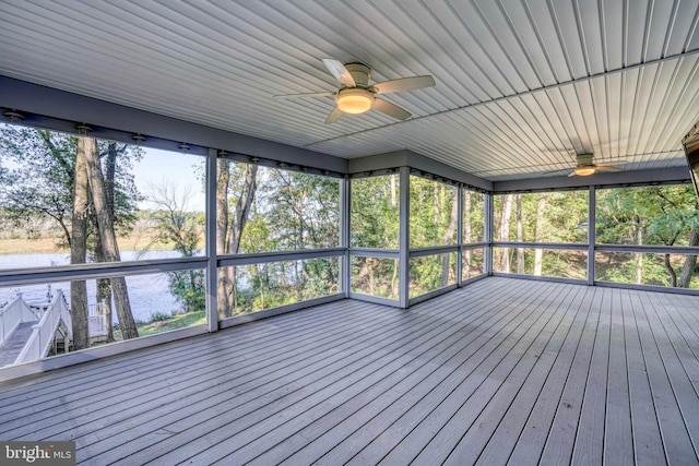 unfurnished sunroom with ceiling fan and a water view
