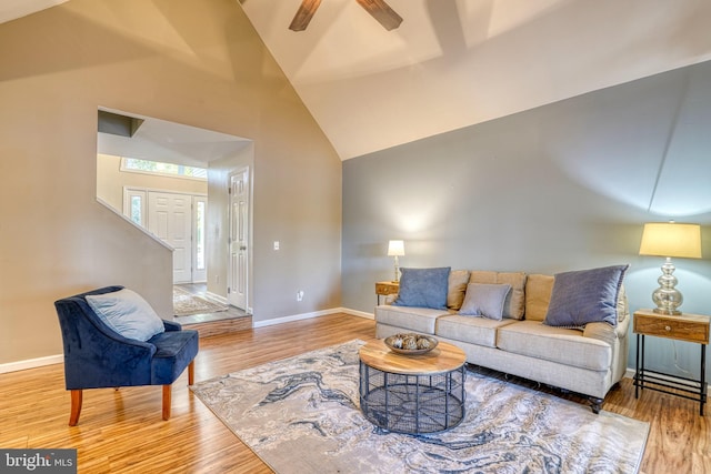 living room featuring light hardwood / wood-style flooring, high vaulted ceiling, and ceiling fan