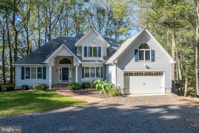 traditional-style home with a front lawn, gravel driveway, a garage, and a shingled roof