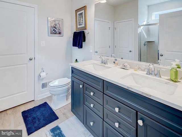 bathroom with wood-type flooring, walk in shower, vanity, and toilet