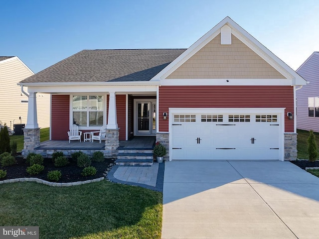 craftsman inspired home with a garage, a porch, a front lawn, and central air condition unit