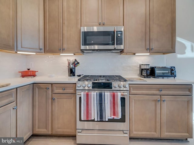 kitchen with stainless steel appliances, light brown cabinetry, and tasteful backsplash