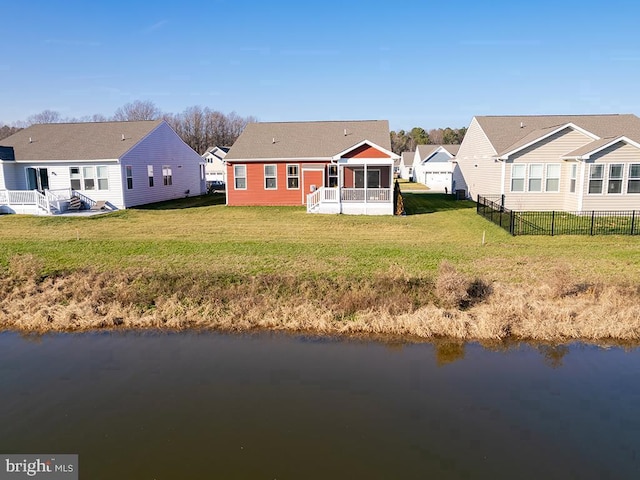 back of property featuring a water view, a yard, and a sunroom