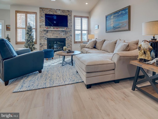 living room with light wood-type flooring, a healthy amount of sunlight, a fireplace, and lofted ceiling