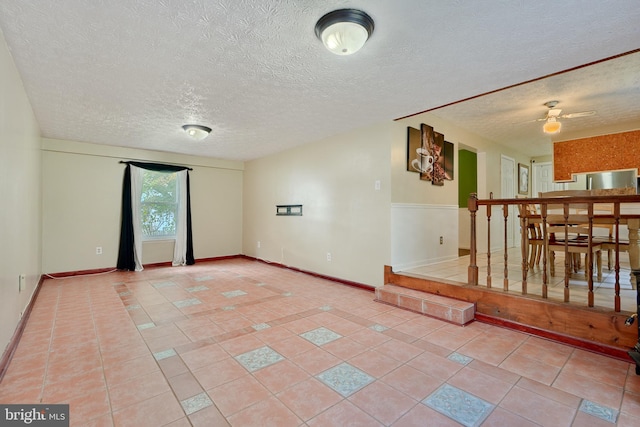 spare room featuring a textured ceiling, light tile patterned floors, and ceiling fan