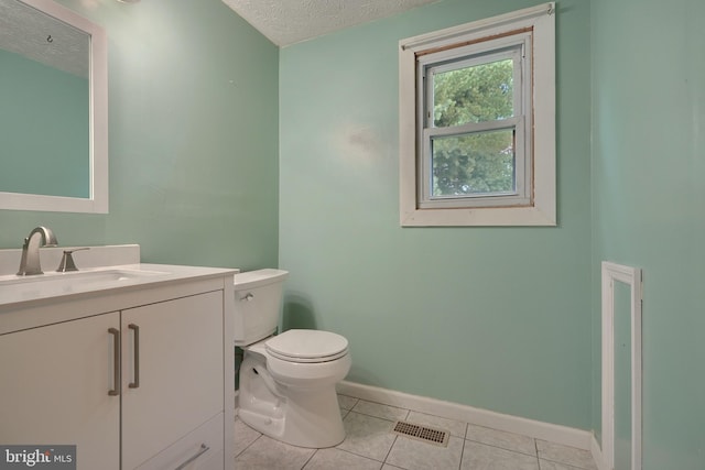 bathroom featuring toilet, vanity, a textured ceiling, and tile patterned flooring