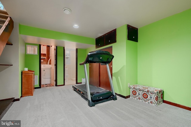 exercise room with light colored carpet and washer / clothes dryer