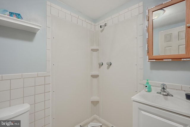 bathroom featuring tile walls, walk in shower, vanity, and toilet