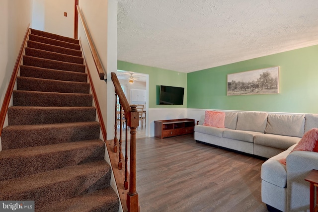 living room with ceiling fan, dark hardwood / wood-style floors, and a textured ceiling