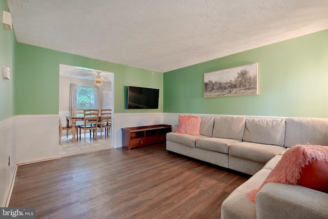 living room featuring hardwood / wood-style floors, ceiling fan, and a textured ceiling