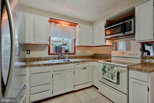 kitchen featuring light tile patterned flooring, a textured ceiling, sink, white cabinets, and white appliances