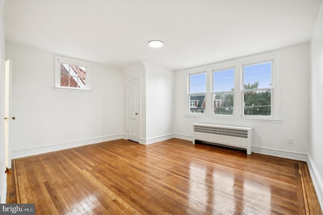 spare room featuring light wood-type flooring and radiator