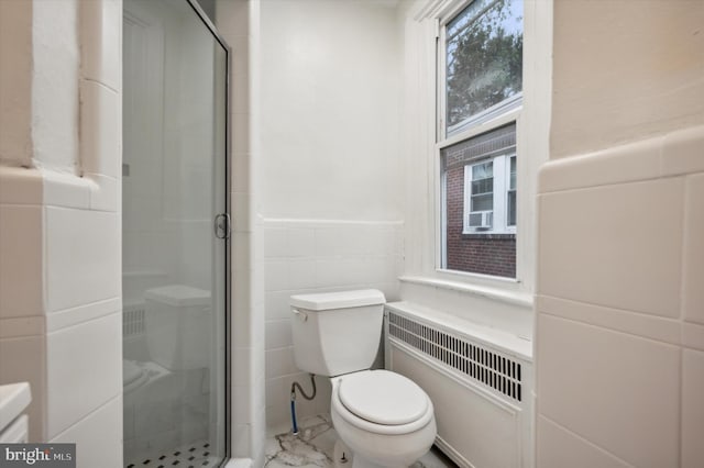 bathroom featuring tile walls, radiator heating unit, a shower with shower door, and toilet