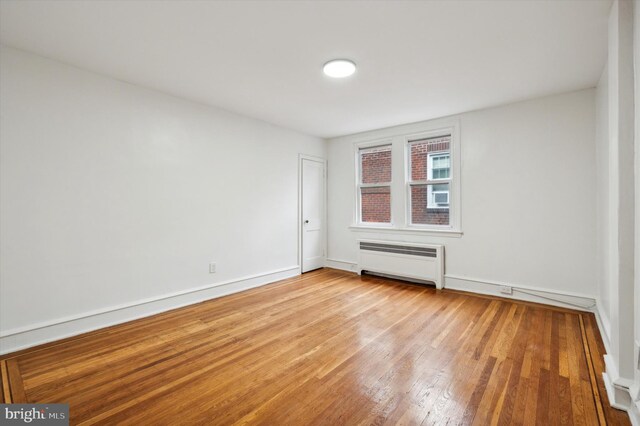 empty room with light wood-type flooring and radiator heating unit