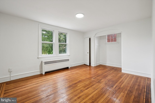 empty room featuring wood-type flooring and radiator